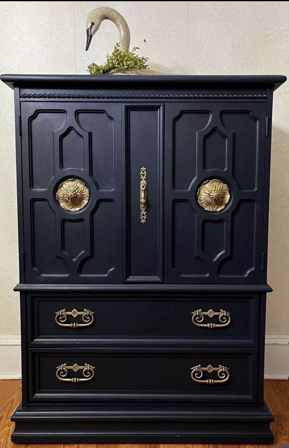 Black armoire with gold decorative details and hardware
