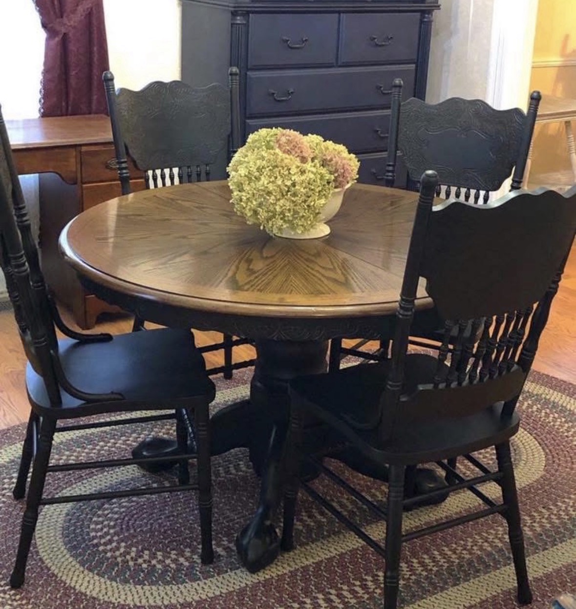 Round dining table with a warm wood top and black chairs